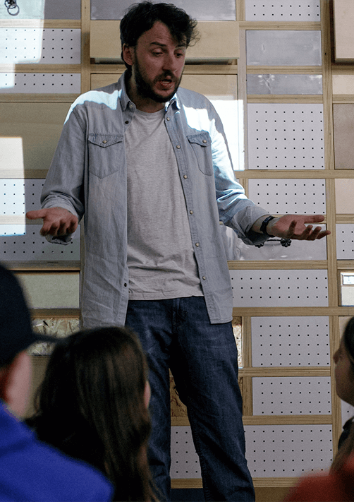 Marcello che spiega i laboratorio ad un gruppo di bambini e bambine